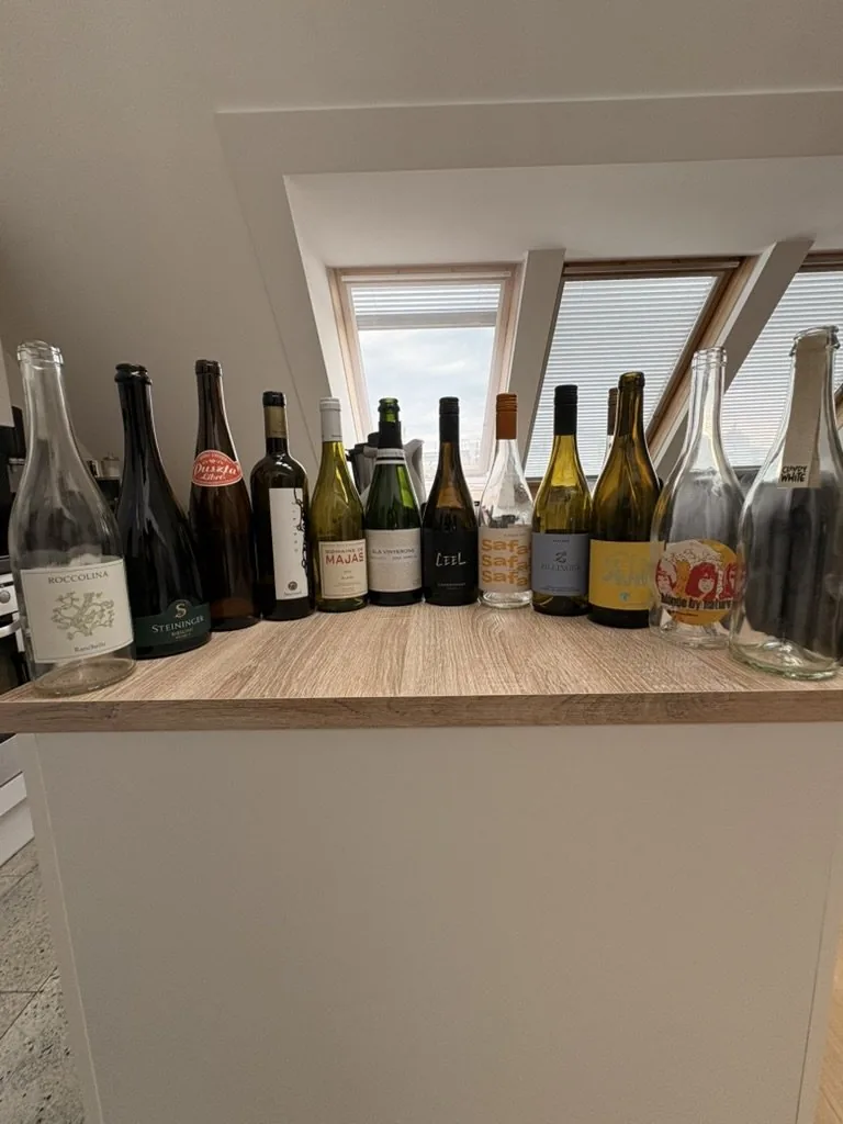wine bottles lined up on a wooden counter beneath skylights